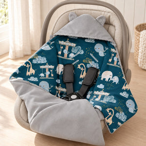 Grey hooded baby car seat blanket with teal amusement park animal lining, styled in a beige infant carrier.