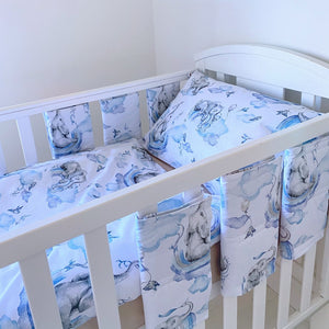 Blue elephant and rainbow nursery bedding set on white background with cot protector wraps