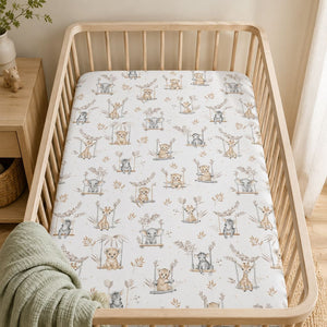 Beige safari baby fitted sheet with elephants, giraffes, zebras and big cats on swings styled in a natural wood cot