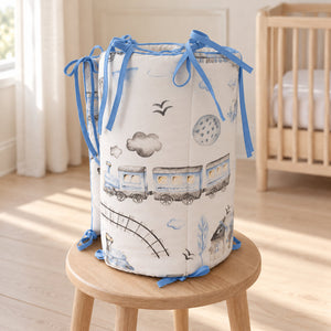 Blue train and aeroplane cotton cot bed bumper displayed in a light wood nursery