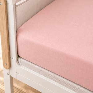 Close-up of a blush pink SnuzPod fitted sheet showing its smooth elasticated fit and cotton texture