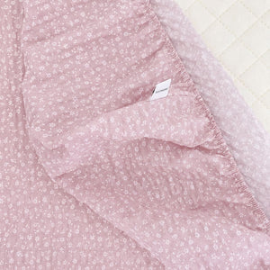 Close-up of dusty pink seersucker cotton fitted sheet showing puckered texture and tiny white floral print
