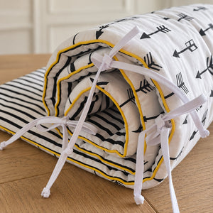 Detail of black arrow cot bed bumper with striped cotton reverse and yellow piping