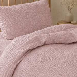 Girls pink single bedding set in textured seersucker cotton with delicate white floral print and natural wood bed