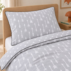 Close-up of light grey arrow-print pillowcase and duvet cover with black piping and a white star reverse in a Scandinavian children’s bedroom