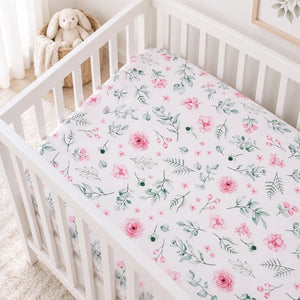 Pink botanical baby cot fitted sheet with watercolour flowers and green leaves in a white Scandinavian nursery
