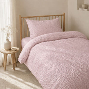 Pink seersucker single bed bedding set with tiny white flowers styled in a Scandinavian girls bedroom