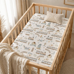 Close-up of baby fitted sheet with blue trains, aeroplanes, railway tracks, trees and clouds on soft cotton