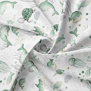 Close-up of Under the Sea 100% cotton fabric from Fabricco UK with mint green ocean animals for children’s sewing and crafts.