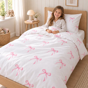 Girl in a Scandinavian bedroom with pink bow kids’ single bed bedding set, 100% cotton duvet cover and pillowcase handmade in the UK.