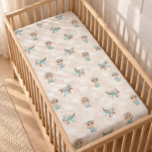 Beige and mint Safari Pilots baby fitted sheet with animal pilots and aeroplanes on a mattress in a wooden cot