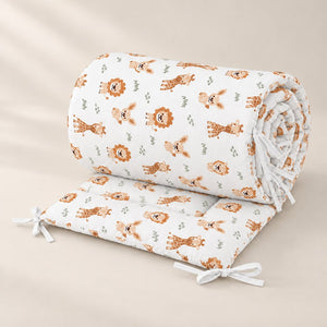 Rolled double-sided safari cot bumper with beige lions, giraffes and soft green details on white cotton, finished with white ties.