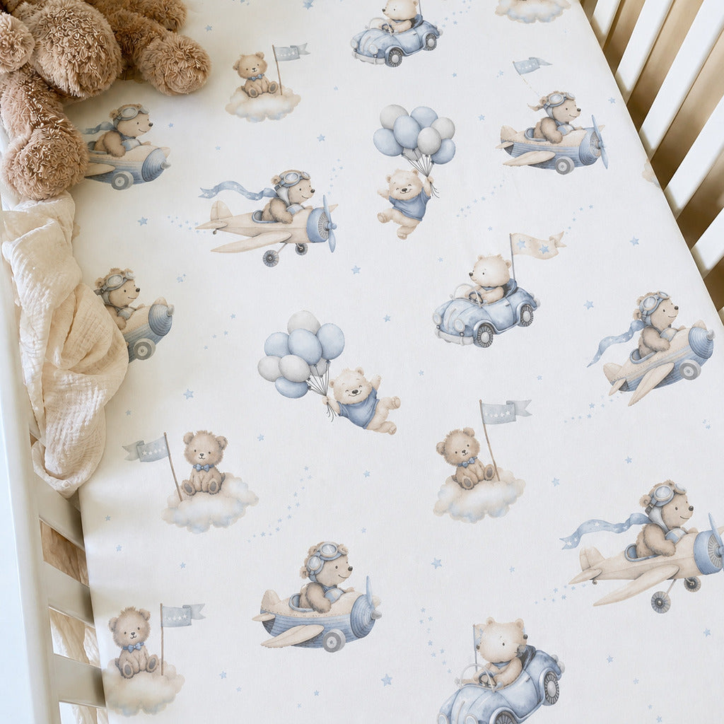 Blue teddy bear aviation baby cot fitted sheet in a light wood cot, made from soft 100% cotton in the UK