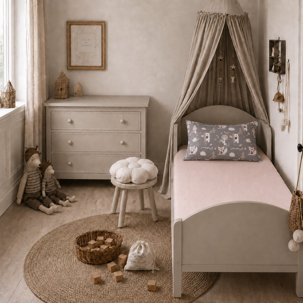 Blush pink single fitted sheet styled with a woodland animals pillowcase on a UK single bed in a neutral children’s bedroom.