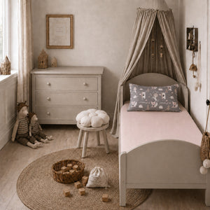 Blush pink single fitted sheet styled with a woodland animals pillowcase on a UK single bed in a neutral children’s bedroom.