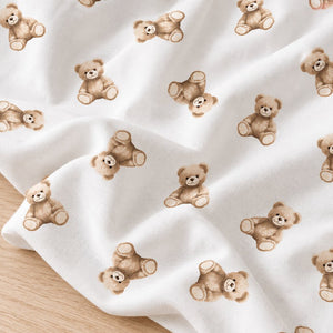 Close-up of soft white cotton fabric with scattered brown teddy bears shown across gentle folds