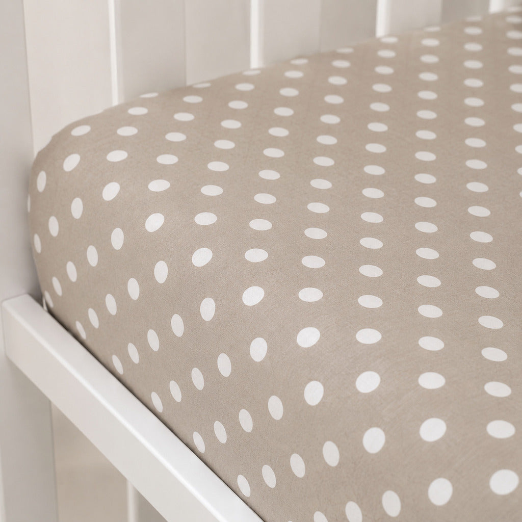 Close-up of a beige cotton single fitted sheet with small white polka dots and a fully elasticated fit.