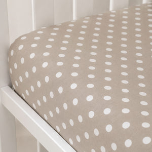 Close-up of a beige cotton single fitted sheet with small white polka dots and a fully elasticated fit.