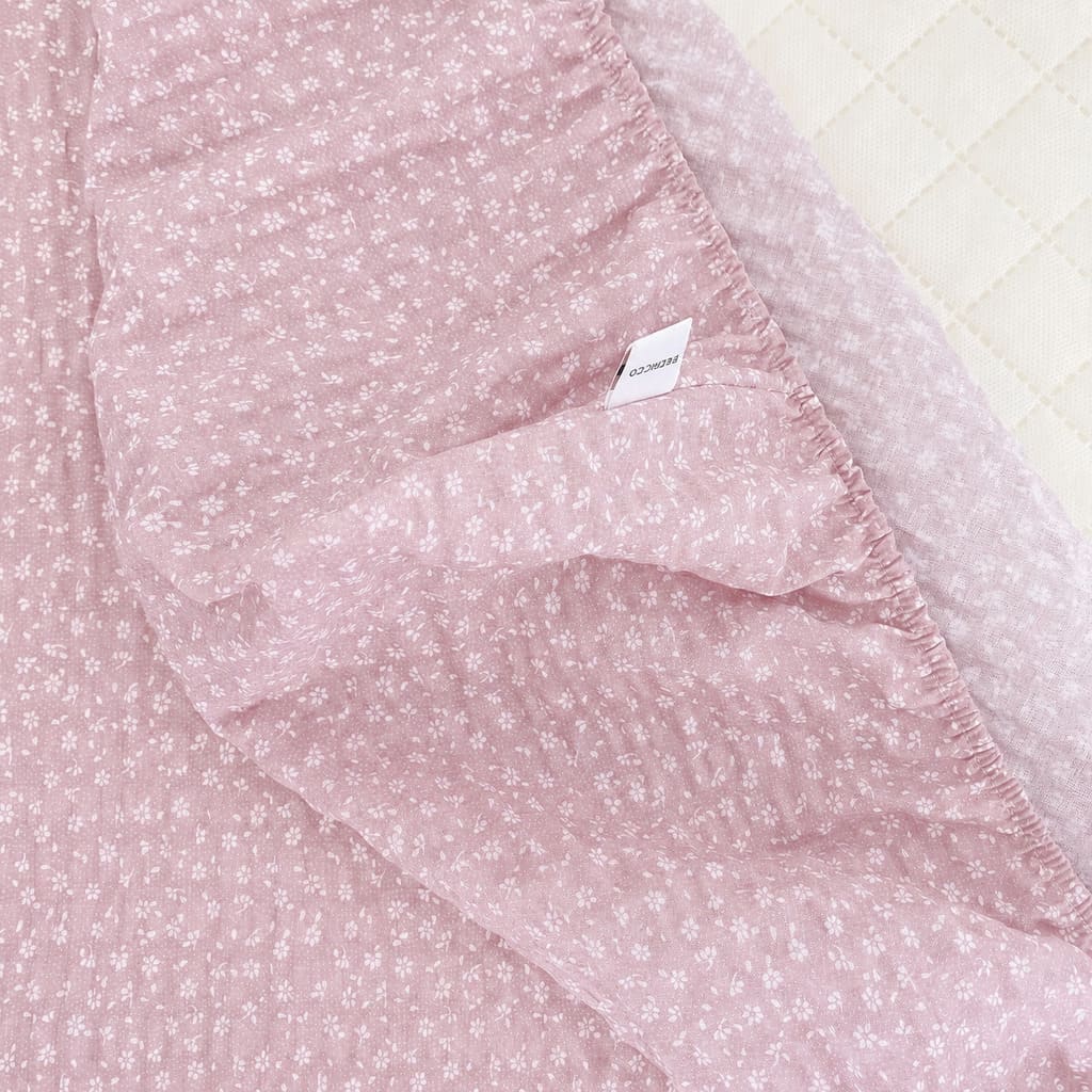 Close-up of dusty pink seersucker cotton fitted sheet showing puckered texture and tiny white floral print