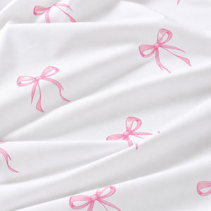 Close-up of white OEKO-TEX® 100% cotton fabric with pink coquette ribbon bows, sold by the metre in the UK.