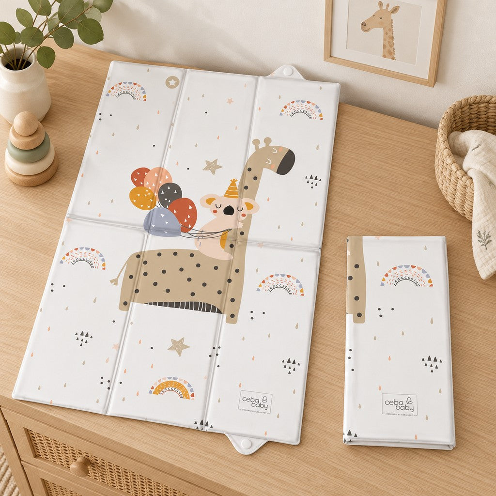 Giraffe and koala travel changing mat displayed open and folded on a wooden nursery dresser.