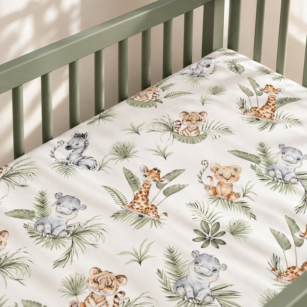 Jungle Animals fitted sheet in a sage green Nestig-style mini crib, beside a light oak table on a natural woven rug.