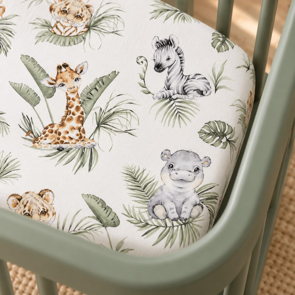 Close-up of the Jungle Animals cotton fitted sheet, showing watercolour giraffes, zebras and hippos among sage green leaves.