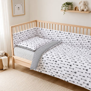 Monochrome arrows cot bedding set with reversible striped design and 180 cm decorative bumper on a standard UK 60 x 120 cm cot.Fabricco UK