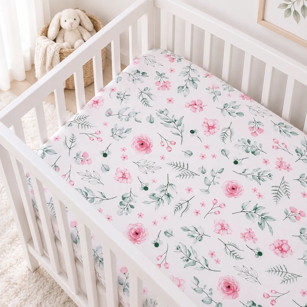 Pink botanical baby cot fitted sheet with watercolour flowers and green leaves in a white Scandinavian nursery