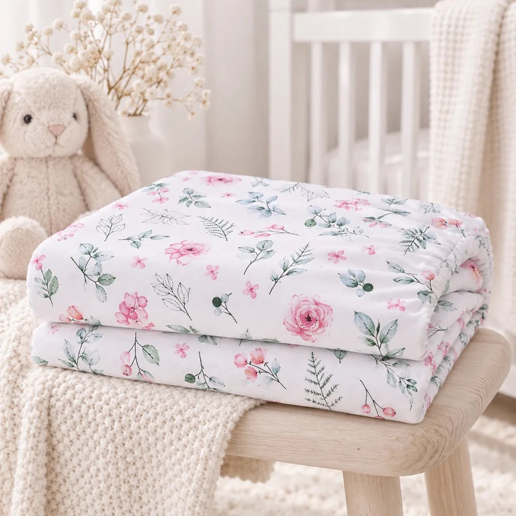 Folded pink botanical baby fitted sheet in 100% cotton with delicate flowers and sage green leaves
