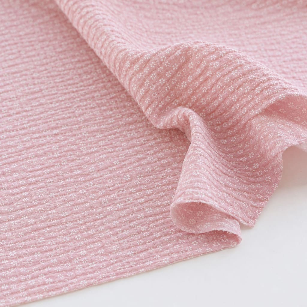 Dusty pink seersucker cotton fabric with tiny white flowers showing the textured puckered finish