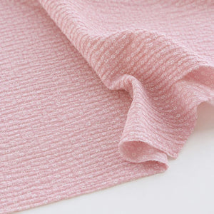 Dusty pink seersucker cotton fabric with tiny white flowers showing the textured puckered finish