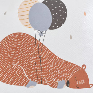 Close-up of the rust-coloured sleeping bear and three muted balloons printed on the white changing mat
