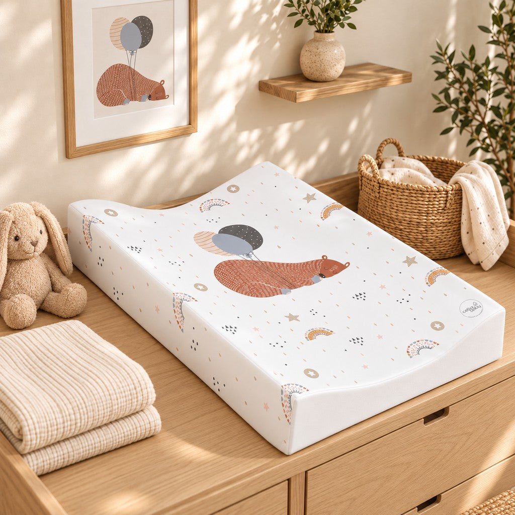 Sleeping bear and balloons changing mat on an oak dresser with matching framed bear artwork, a beige bunny and woven basket