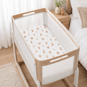 SnuzPod bedside crib with natural beige safari animals fitted sheet featuring lions, giraffes and fawns, handmade from 100% cotton for a neutral nursery.
