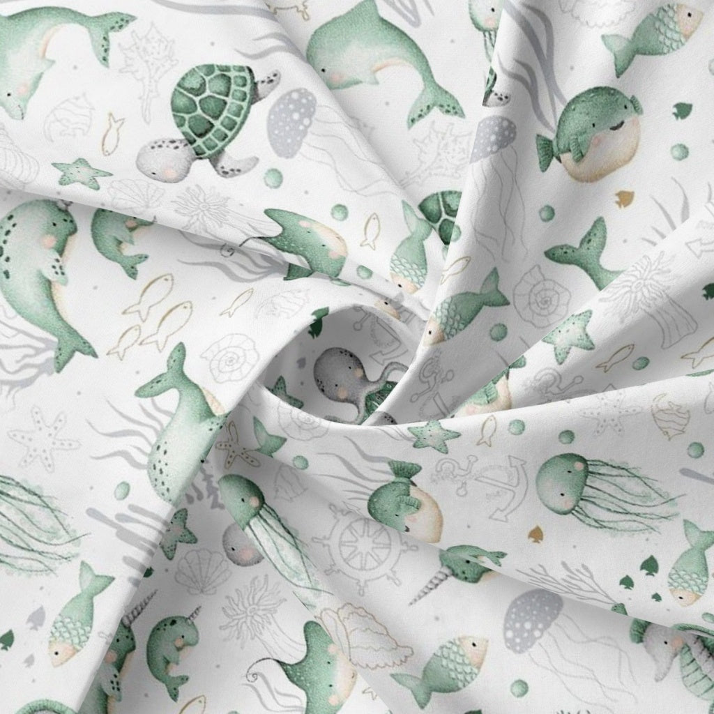 Close-up of Under the Sea 100% cotton fabric from Fabricco UK with mint green ocean animals for children’s sewing and crafts.