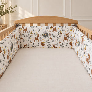 Woodland animals padded cot bumper fitted to a natural oak UK cot, 30 × 180 cm three-panel OEKO-TEX® cotton cot wrap.