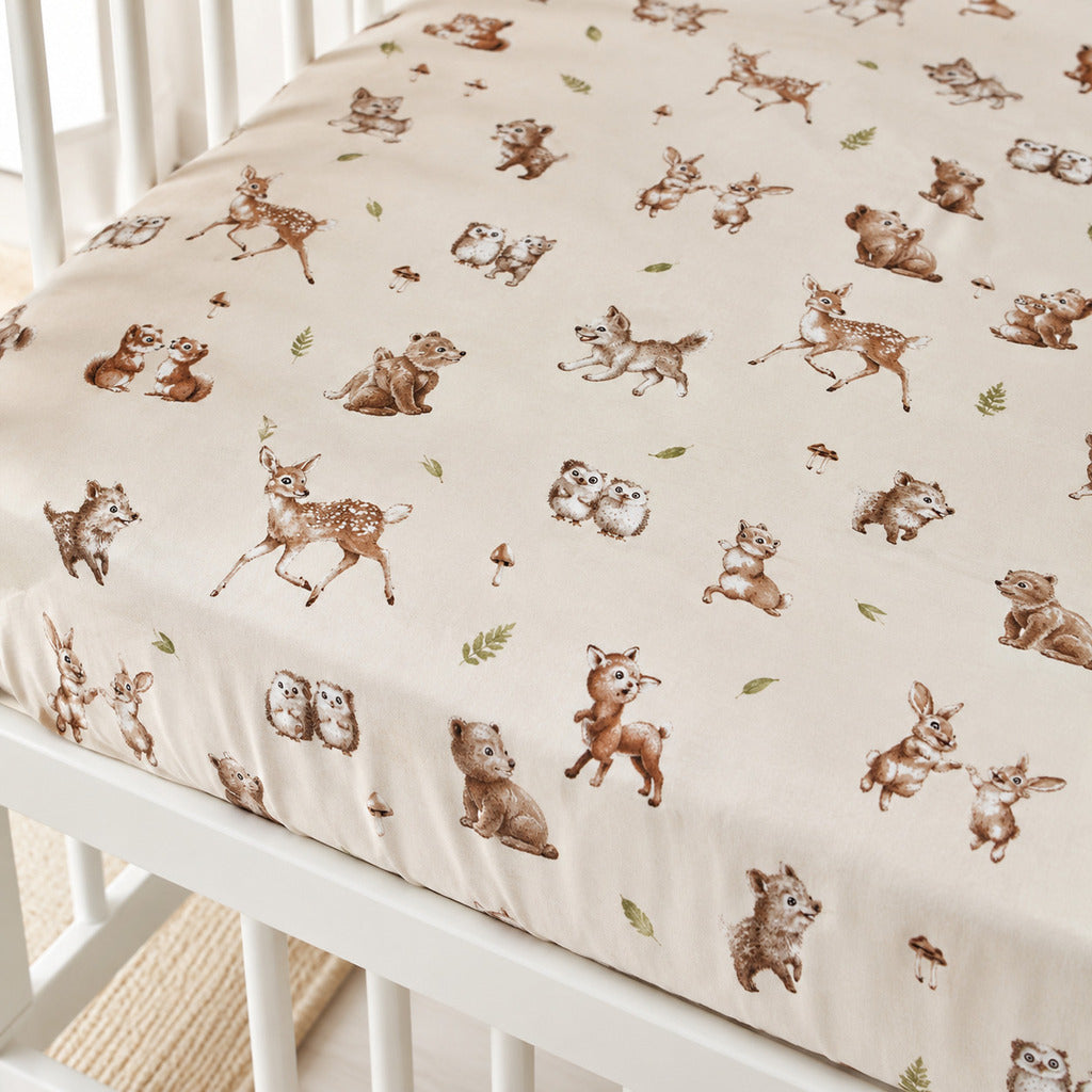 Crib sheet with forest animal pattern on a white crib