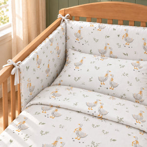 Close-up of Little Goose cotton duvet cover, pillowcase and decorative cot bumper, featuring grey geese, sage green leaves and golden bows.