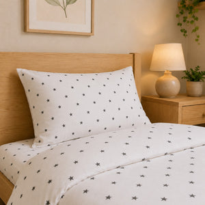 Close up of white cotton pillowcase and duvet cover with black star print for single bed