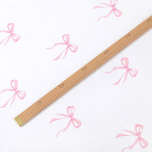 Pink bow cotton fabric shown with a centimetre ruler to demonstrate the motif size and pattern repeat