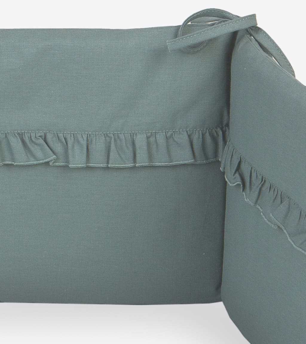 Handmade sage green cot bumper with ruffle detail, fitted to a 120x60 cm baby cot, soft breathable nursery cot protector for safe sleep in UK nurseries.