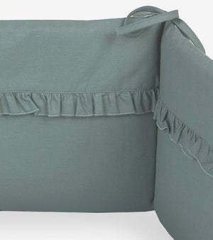 Handmade sage green cot bumper with ruffle detail, fitted to a 120x60 cm baby cot, soft breathable nursery cot protector for safe sleep in UK nurseries.